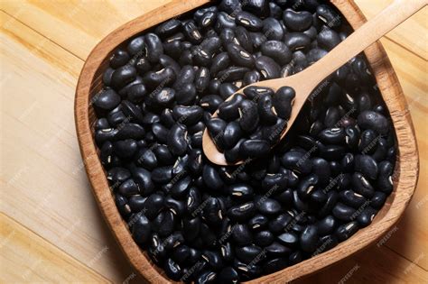 Premium Photo | Black soy beans in wooden scoop isolated on wood table ...