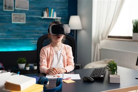 Little pupil at home desk using vr glasses for class | Free Photo