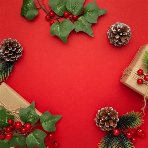 Gui, pommes de pin et cadeaux de Noël sur table rouge | Photo Gratuite