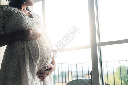 孕妇在照顾孩子的同时在家感到快乐年轻的准妈抱着婴儿在怀孕的肚子里产前护理和高清图片下载-正版图片506132923-摄图网