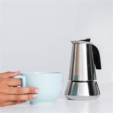 Close-up mão segurando chaleira e caneca | Foto Grátis