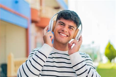 Young hispanic man at outdoors listening music | Premium Photo
