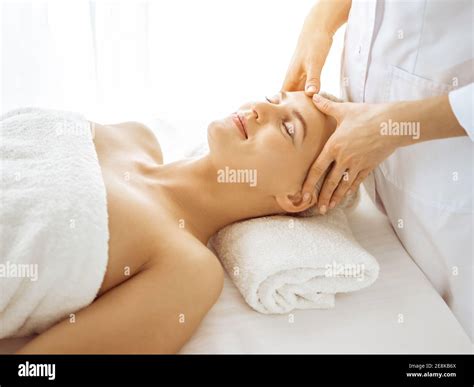 Beautiful blonde woman enjoying facial massage with closed eyes in ...