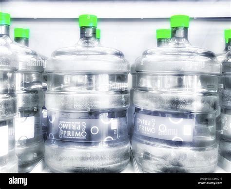 5 gallon bottles of purified, filtered water are seen on a rack for ...