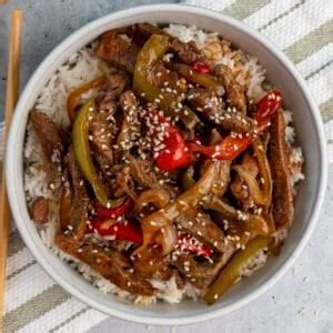 A bowl of slow cooker pepper steak, served over white rice