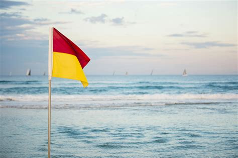 Red And Yellow Flag Standing Near Beach · Free Stock Photo