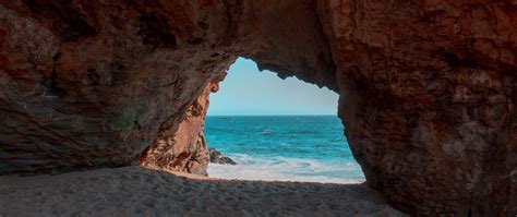 Download wallpaper 2560x1080 beach, rock, cave, sea, sand, water dual ...
