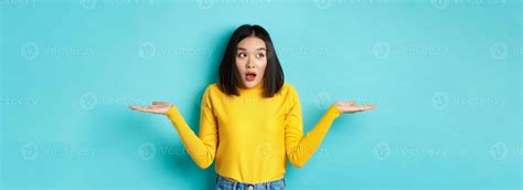 Confused and shocked asian woman dont understand, shrugging with spread ...