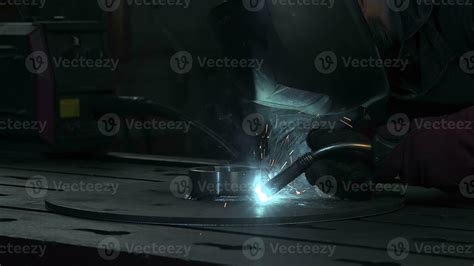 Masked worker is welding metal structures. Creative. Welding sparks fly during work of welder at ...