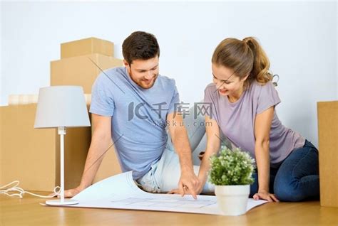 抵押贷款、人和房地产概念-幸福的夫妻带着盒子和蓝图搬到新家。高清摄影大图-千库网