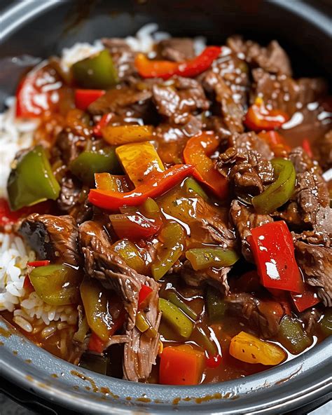 A bowl of slow cooker pepper steak, served over white rice