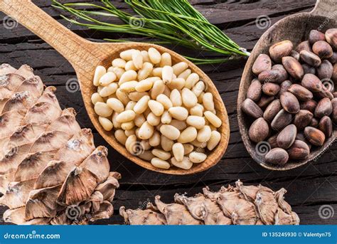 Pine Nuts in the Spoon and Pine Nut Cone on the Wooden Table. Organic ...