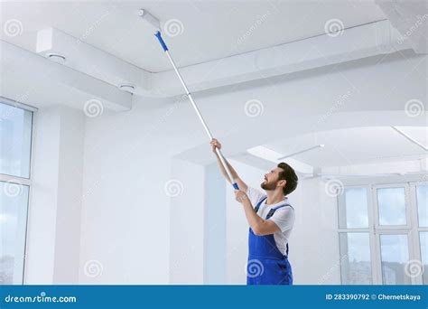 Handyman with Roller Painting Ceiling in Room Stock Photo - Image of ...