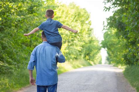 A happy child on the shoulders of a parent in nature on the way to ...