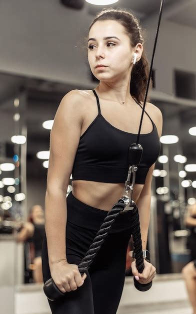 Jovem em forma treina tríceps misci na máquina de exercícios crossover ...