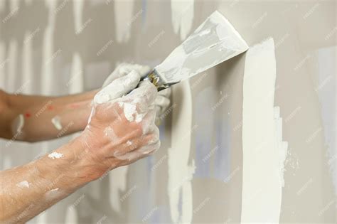 Premium Photo | Worker applying spackle to drywall with a putty knife