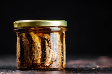 Sprats in a glass jar on the table | Premium Photo