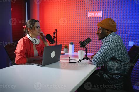 two radio hosts in headphones laughing while recording podcast in ...