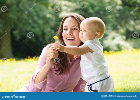 愉快的拿着花的母亲和孩子在公园 免版税库存照片 - 图片: 32549795