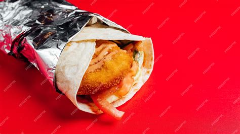 Premium Photo | Closeup of chicken wing wrap rolled in tin foil on a ...