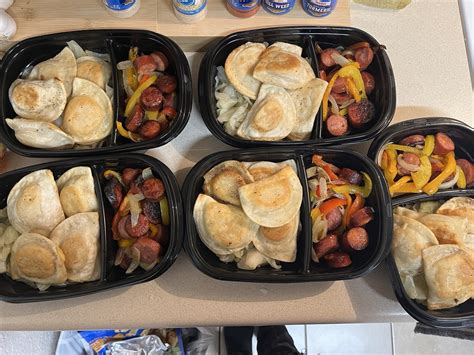 A plate with pierogies sausages and cabbage served with a small bowl of sour cream