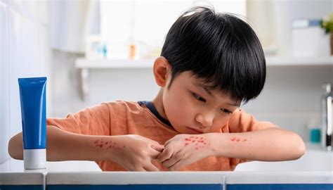 A young child standing in a brightly lit bathroom looking at a red rash ...