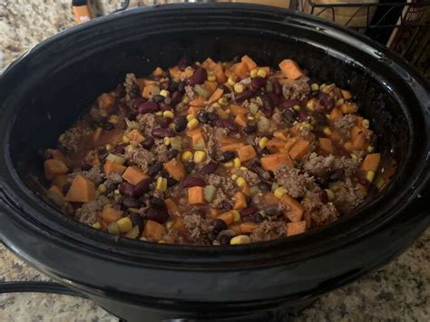 A bowl of Laura's quick slow cooker turkey chili, topped with shredded cheese, sliced green onions,