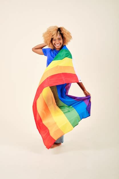 Smiling curly hair woman holding an lgbt pride rainbow flag while ...