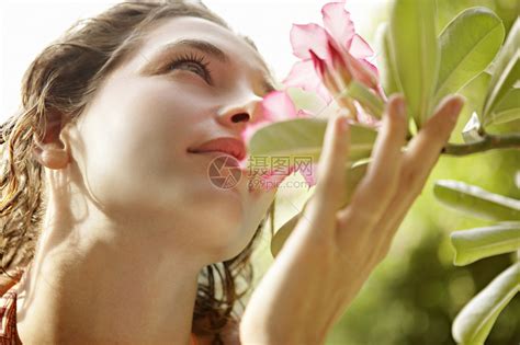 近距离看到一个美丽的年轻女子拿着一朵花靠近她的鼻子高清图片下载-正版图片504748612-摄图网