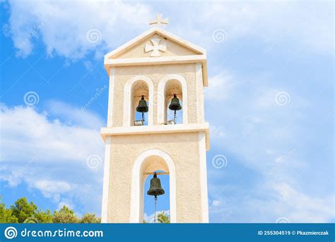 The façade of a masonry building, with four Greek adorning its entrance, under a clear blue sky