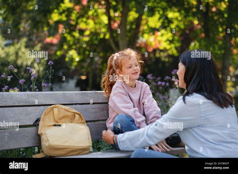 Adult daughter talking to her senior parents on a bench in a park