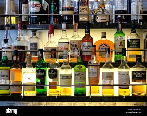 Selection of Whiskeys and other Alcoholic Spirits on a Lit Glass Shelf ...