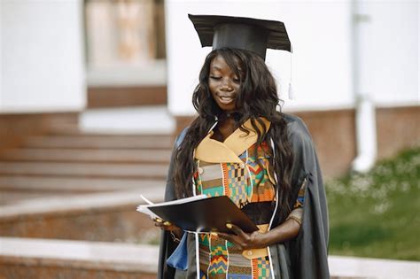 Junge afroamerikanische Studentin in schwarzem Abschlusskleid gekleidet ...