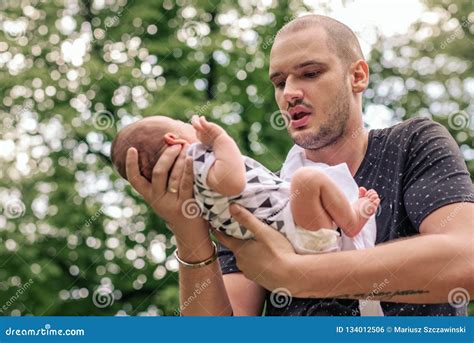 Young Father Cradling His Baby Boy in His Hands Outside Stock Photo ...