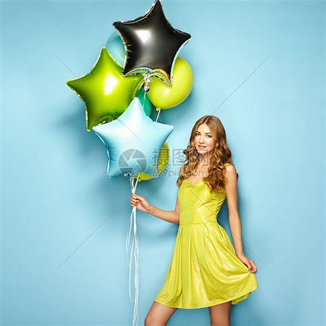 美丽的轻女人,蓝色背景上五颜六色的气球生日派节日里穿绿色衣服的女孩高清图片下载-正版图片300181793-摄图网