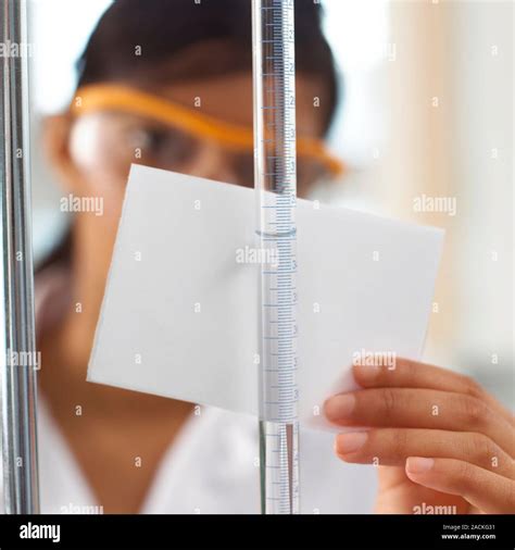 Titration experiment. Student using a piece of white card to ...