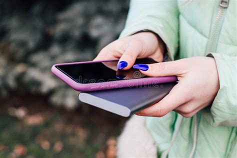 一个蓝指甲的女孩，手里握着一个手机，放在一个箱子里，和一个充电的电源库 库存图片 - 图片 包括有 充电器, 电缆: 166125535