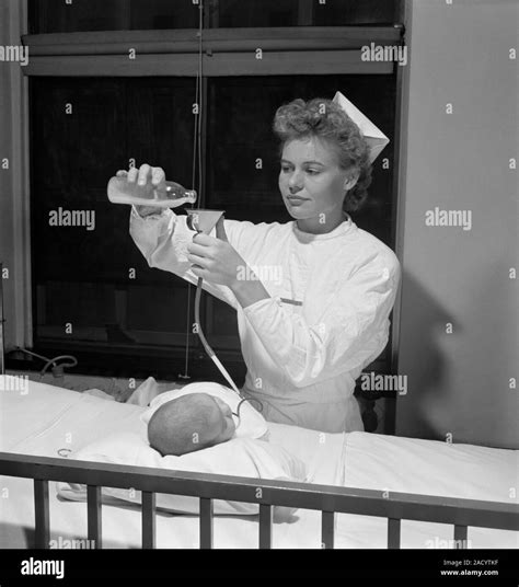 Infant tube feeding. Nurse in the 1940s being trained in a US hospital ...