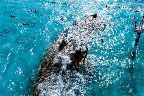 Pessoa em um barco com outra pessoa praticando snorkel ao lado do barco