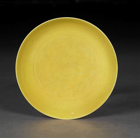 A small incised yellow-glazed 'dragon and phoenix' dish, Yongzheng six ...