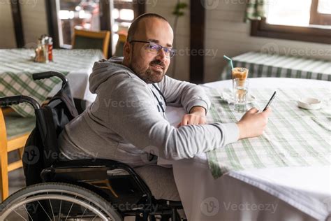 Happy paraplegic handicapped man in wheelchair is sitting at restaurant ...