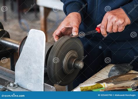 Male Sharpener Sharpens a Knife Blade on a Knife Sharpening Machine in ...