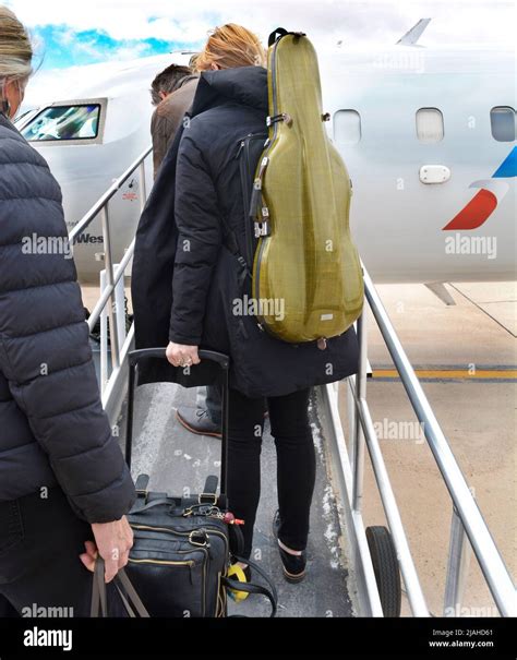 A passenger carrying a musical instrument as carry-on luggage boards an ...