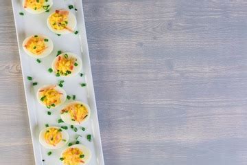 Deviled eggs garnished with green onions and bacon. | Premium Photo