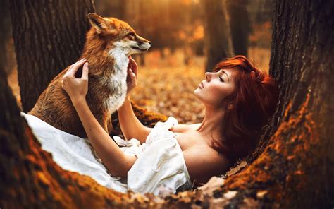 Red-Haired Woman with a Red Fox in Autumn Forest by Marketa Novak