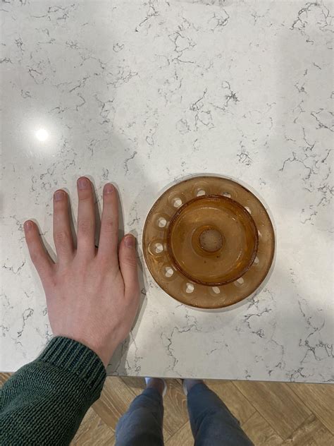 Orange glass circular object with central well and wholes around edge ...