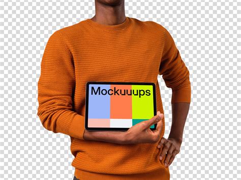 Man in orange sweather holding iPad mockup in landscape - Mockuuups Studio