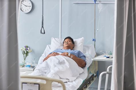 Premium Photo | Senior female patient sleeping on bed in hospital room with tubes and IV support