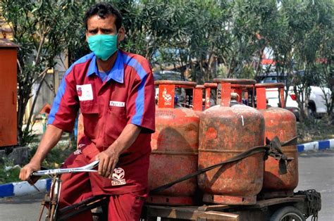 A delivery man carrying LPG cylinders rides past
