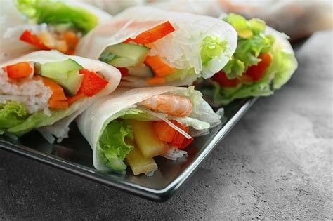 Plate with fresh spring rolls in rice paper on table | Premium Photo